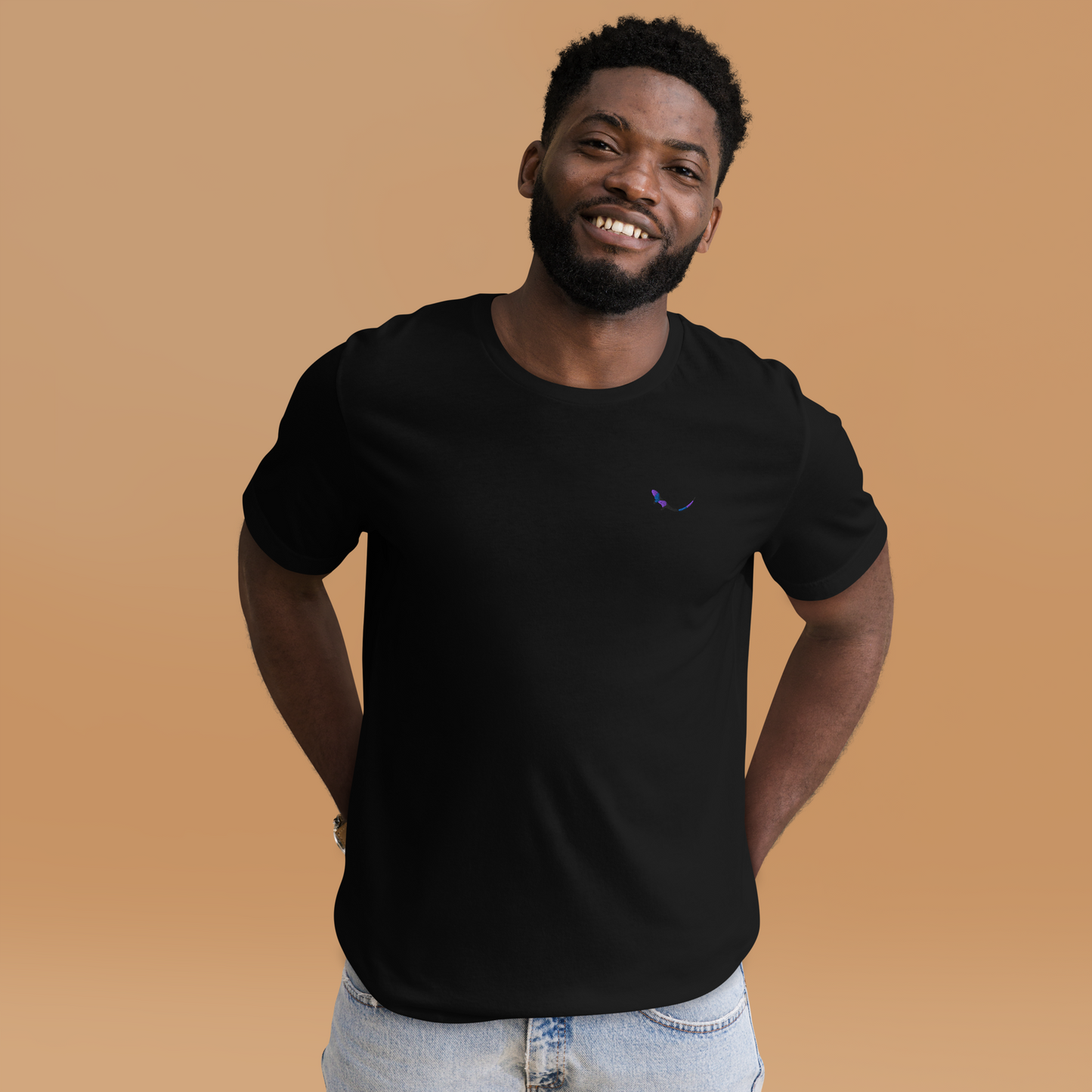 A smiling man wearing THE SUBTROPIC Global Tee in black, showcasing its comfortable fit and embroidered logo.